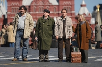 Szenenfoto aus &quot;Das Konzert&quot;: Sascha (Dimitri Nazarow), Iwan (Valeri Barinov), Andrej (Alexej Guskow) und seine Frau Irina (Anna Kamenkowa Pawlowa) warten auf den Bus nach Paris.
