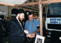 Rabbiner Teichtal legt einem jüdischen Besucher des Straßenfestes Tfillin an